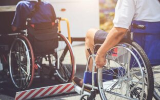 Rollstuhlfahrer beim einsteigen in einen Reisebus mithilfe von einem Lift