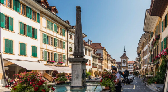 Senioren an einem Brunne in der Innenstadt von Murten - Tagesausflug an den Murtensee mit Born Reisen