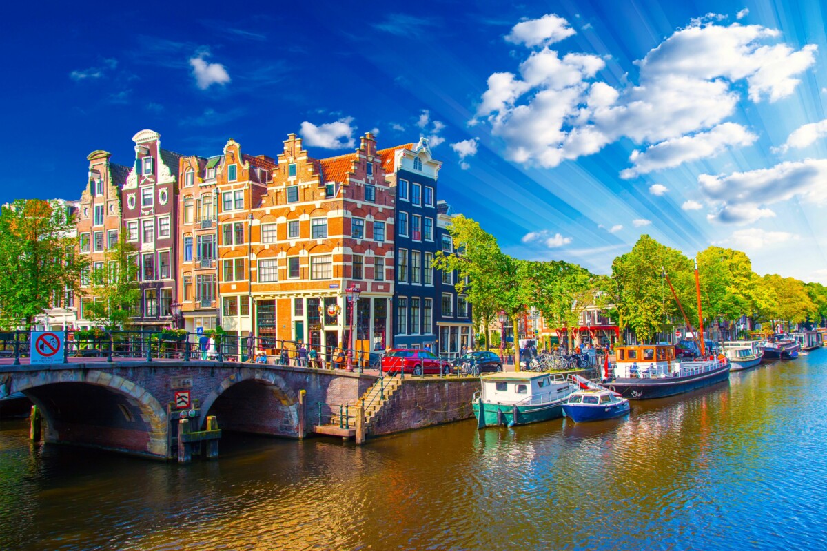 Romantische Grachten in Amsterdam mit historischen Häusern und typischen Booten bei sonnigem Wetter.