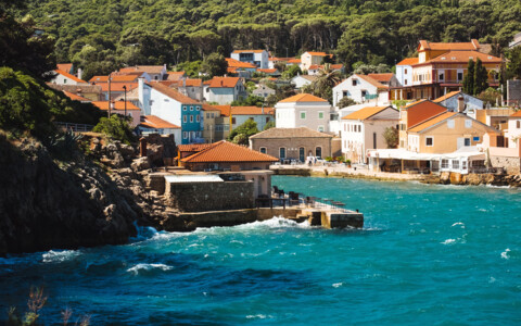 Küstenort auf der Insel Lošinj in Kroatien mit bunten Häusern und tiefblauem Meer.