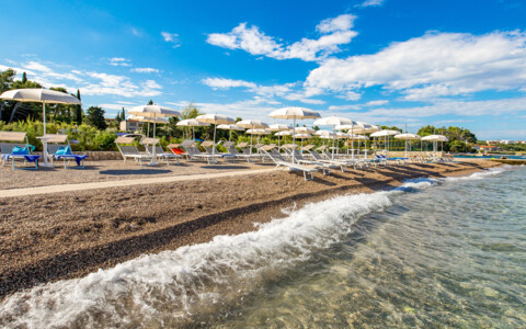 Privatstrand des Hotel Malin auf der Insel Krk mit Liegen, Sonnenschirmen und klarem Wasser.