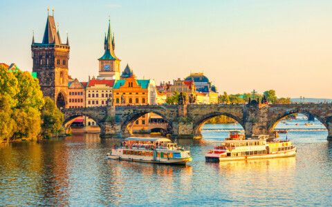 Abendliche Aussicht auf die Karlsbrücke in Prag mit Moldau-Schifffahrt – beliebtes Reiseziel für Städtereisen.