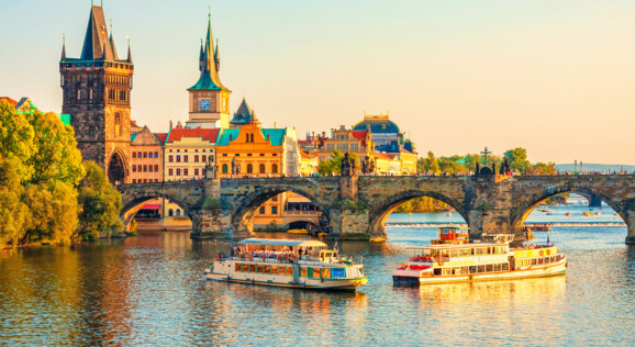Abendliche Aussicht auf die Karlsbrücke in Prag mit Moldau-Schifffahrt – beliebtes Reiseziel für Städtereisen.
