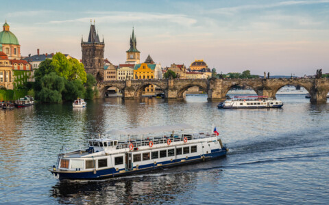 Ausflugsschiff auf der Moldau in Prag mit Blick auf die Karlsbrücke und die historische Altstadt.