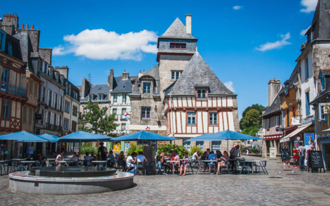 Der lebendige Marktplatz von Quimper, umgeben von Fachwerkhäusern und historischen Gebäuden, wo Einheimische und Besucher regionale Produkte kaufen.