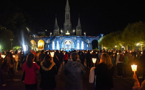 Pilger bei der Lichterprozession in Lourdes mit Kerzen in der Nacht