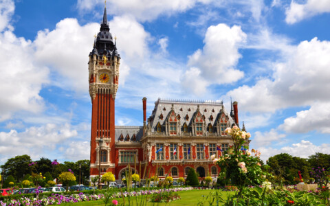 Rathaus von Calais mit markantem Belfried und gepflegter Parkanlage im Stadtzentrum.