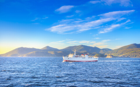 Reisende geniessen die Fährfahrt nach Elba mit Panorama auf Meer und Insel.