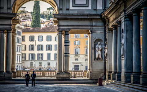 Blick durch die Arkaden der Uffizien auf historische Gebäude im Zentrum von Florenz.