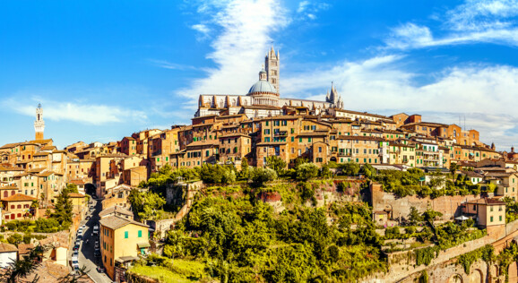 Blick auf die historische Altstadt von Siena in der Toskana mit dem Dom von Siena und den charakteristischen Häusern der Stadt.