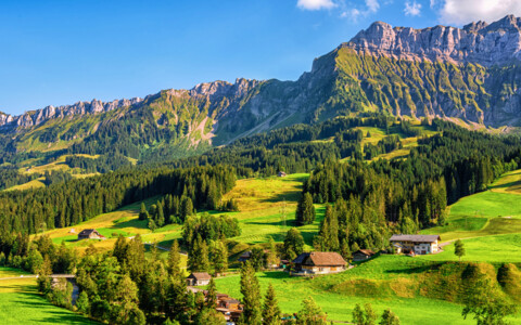 Sommer in Schangnau – grüne Hügel, traditionelle Bauernhäuser und Alpenpanorama im Emmental.