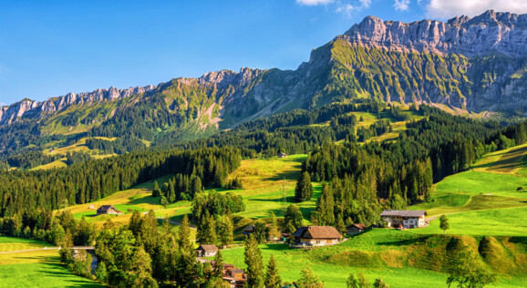 Sommer in Schangnau – grüne Hügel, traditionelle Bauernhäuser und Alpenpanorama im Emmental.