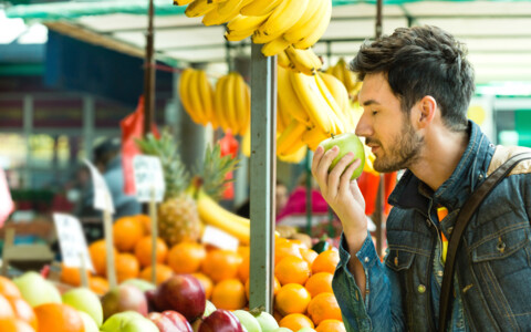 Mann auf Markt in Luino, riecht an einem Apfel, Tagesausflug mit dem Bus nach Luino