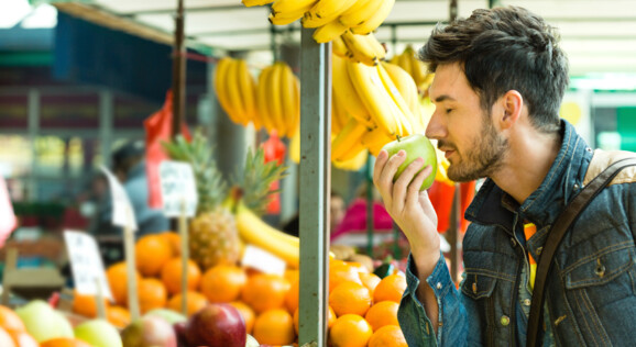 Mann auf Markt in Luino, riecht an einem Apfel, Tagesausflug mit dem Bus nach Luino