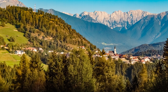 Blick auf Seefeld in Tirol mit herbstlicher Berglandschaft und den markanten Gipfeln der Alpen im Hintergrund. Arztal