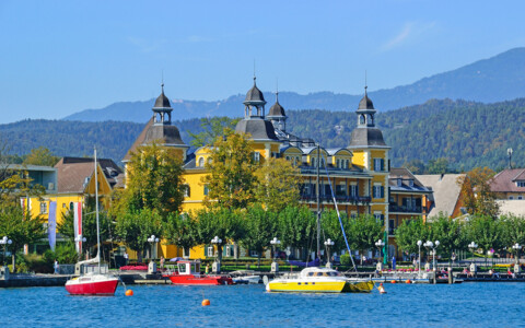 Schlosshotel Velden direkt am Wörthersee mit Promenade und eindrucksvoller Kärntner Bergkulisse.