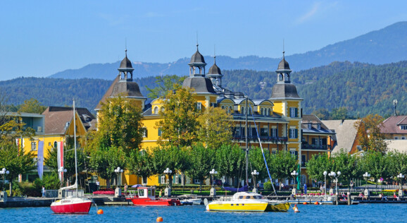 Schlosshotel Velden direkt am Wörthersee mit Promenade und eindrucksvoller Kärntner Bergkulisse.