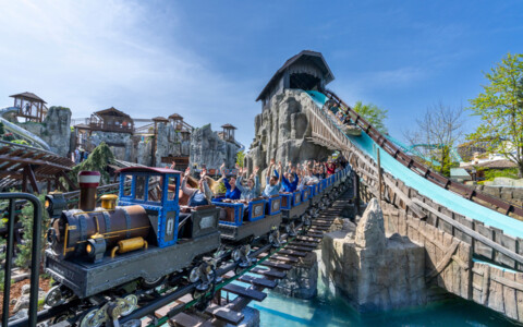 Alpenexpress Enzian im Europa-Park Österreich mit fröhlichen Fahrgästen auf der Bergstrecke im Frühling.